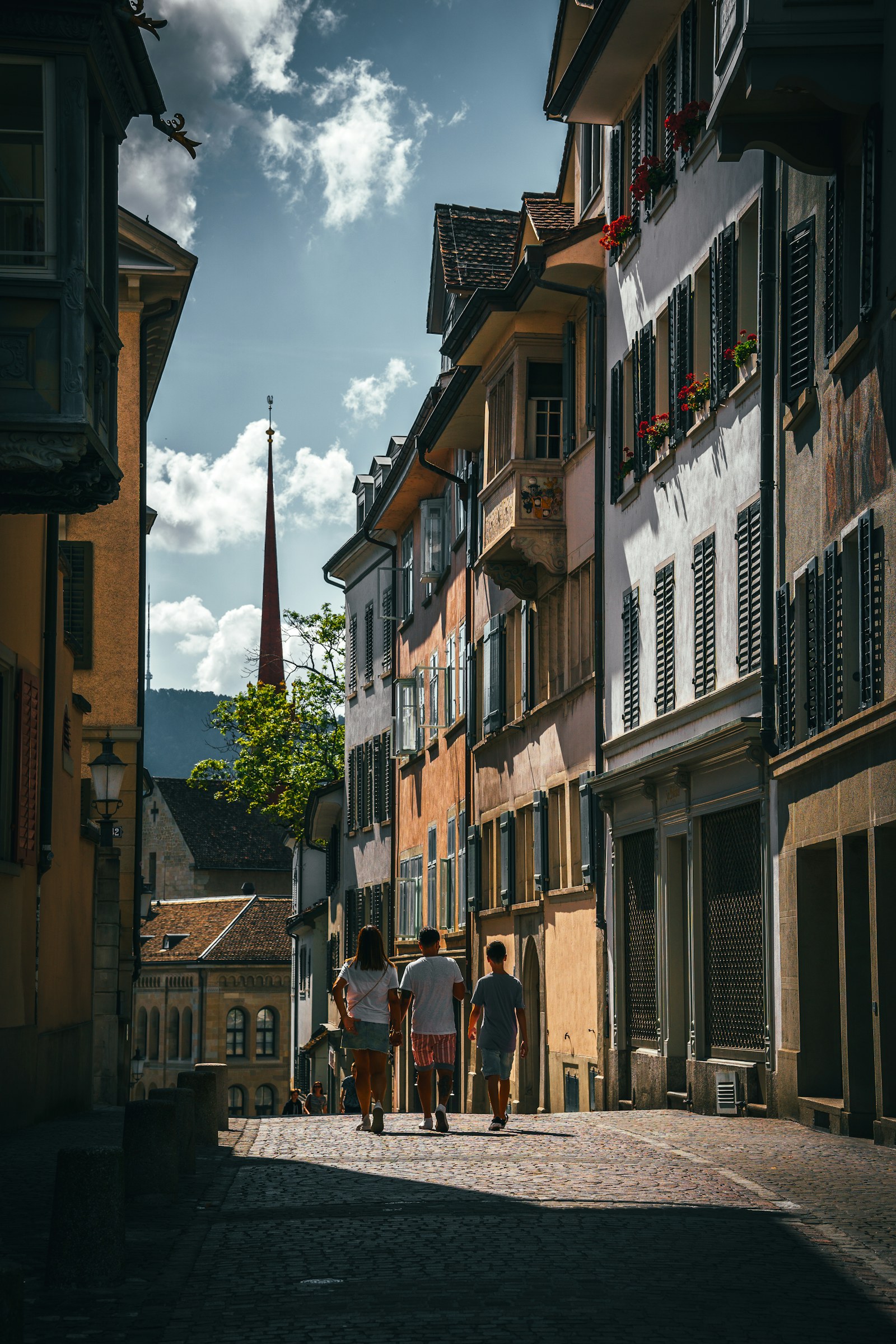 Peatones cruzan una calle de Zúrich rodeada de edificios históricos.